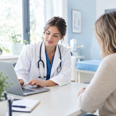 Une médecin consulte le dossier patient sur son ordinateur portable pendant une consultation avec sa patiente